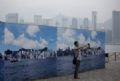 Hong Kong instala painis de cu claro para driblar poluio em fotos Homem tira foto de painel fotogrfico que mostra Hong Kong; ao fundo, o horizonte real coberto pela poluio (Foto: Jerome Favre/Bloomberg via Getty Images)