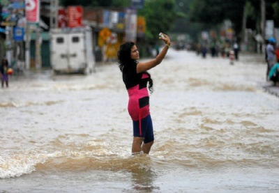 Apesar de caos, mulher faz selfie no meio de rua inundada no Sri Lanka Apesar do caos que as fortes chuvas provocaram no Sri Lanka, jovem fez selfie no meio de rua inundada (Foto: Dinuka Liyanawatte/Reuters)